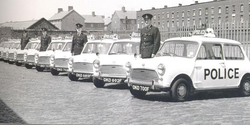 A line-up of black-and-white Liverpool police Minis with roof-mounted POLICE boards and warning lamps